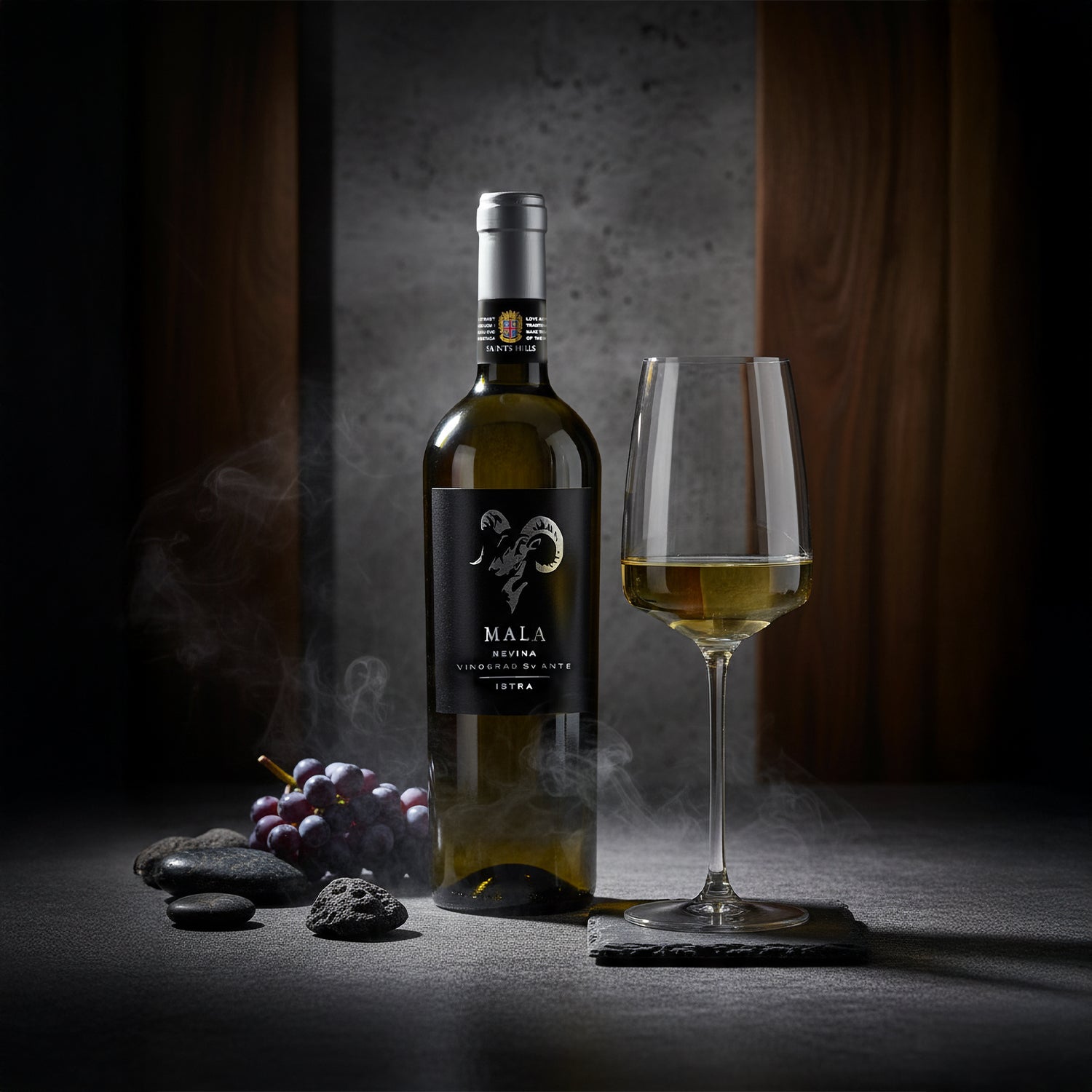 Elegante Szene mit einer Flasche Saints Hills Mala Nevina Weißwein, einem gefüllten Weinglas, dunklen Trauben und Steinen vor mysteriösem Hintergrund