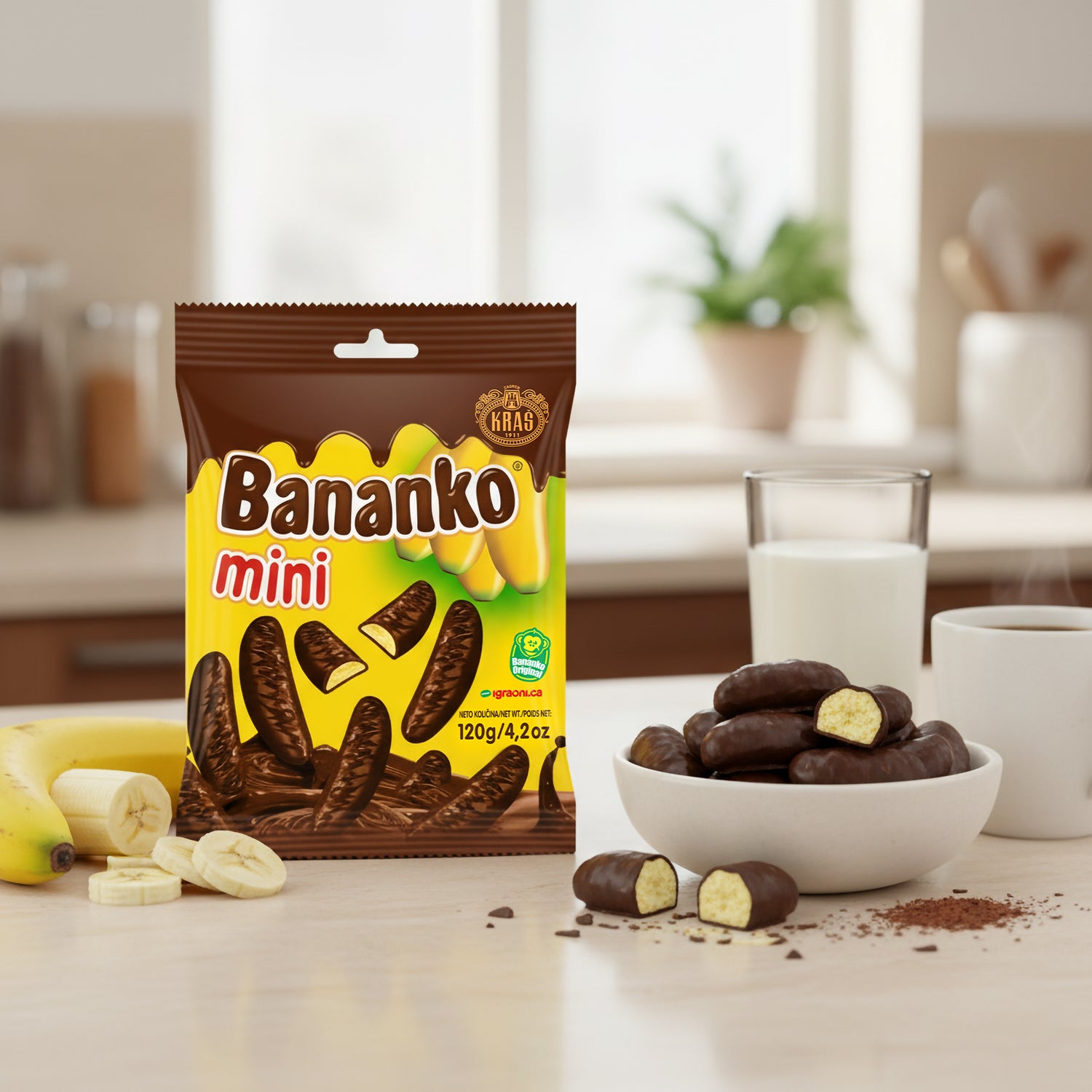 Eine Tüte Kraš Bananko mini neben einer Schale mit den Schokobananen, serviert als süßer Snack zu Kaffee und Milch